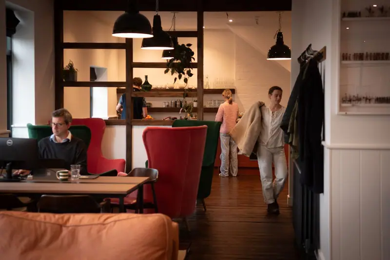 People talking at tables in an informal, light-filled workspace