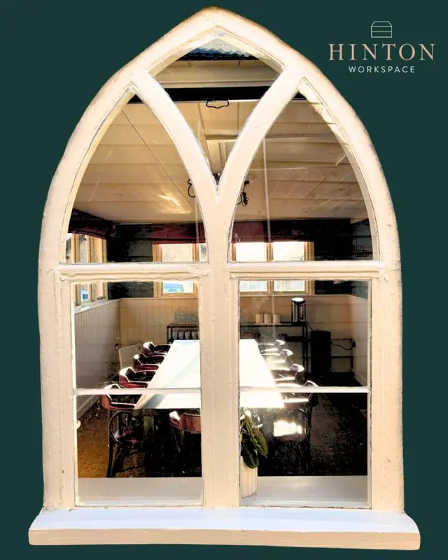 An arched window looking onto a meeting table in the Hinton workspace