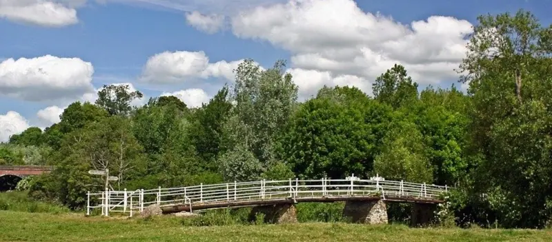 A footbridge crossing the river through green parkland